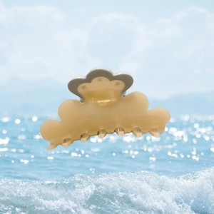 Detail view of a cream-colored cloud hair claw clip with grey edges and spring design