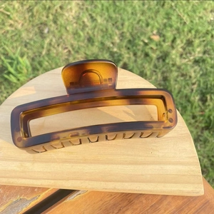 Close-up of tortoise shell pattern hair claw clip on wooden display in nature setting