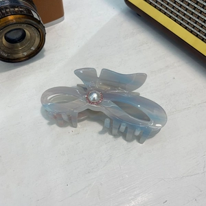 Detalle de pinza para el pelo en acetato marmoleado con perla central y diamantes rosas