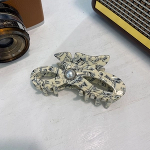 Detalle de la pinza de acetato con textura de mármol, perla y pedrería brillante