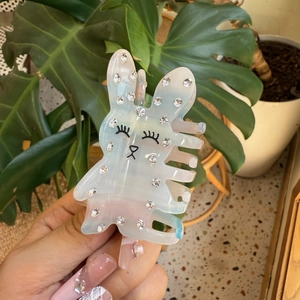 Détail de la pince à cheveux lapin nacré avec strass et visage de dessin animé