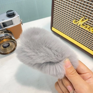 Détail montrant la texture douce en fausse fourrure grise de la grande pince à cheveux
