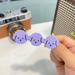 Dettaglio di tre piccoli fermagli per capelli a forma di cane viola in acetato con design cute