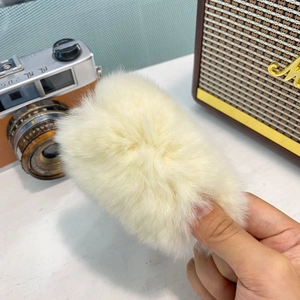 Détail d'une pince à cheveux en peluche blanc crème avec une texture de fourrure douce