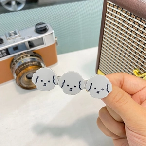 Dettaglio del fermaglio triplo in acetato con teste di cucciolo bianco stile cartone animato