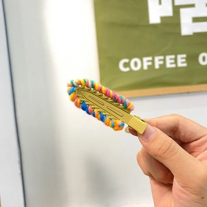 Close-up of colorful hand-woven yarn hairpin with durable metal duckbill clip