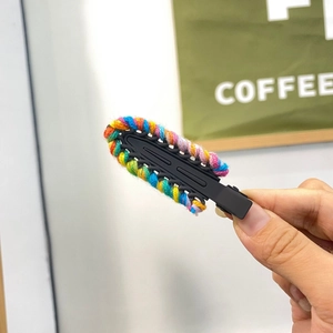 Detailed close-up of handmade candy color knit hair clip with rainbow weave texture