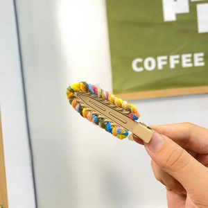 Close-up of colorful knitted yarn hair clip with handmade woven texture and clip detail
