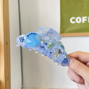 Light blue acetate hair claw clip with sparkling rhinestones in a floral pattern