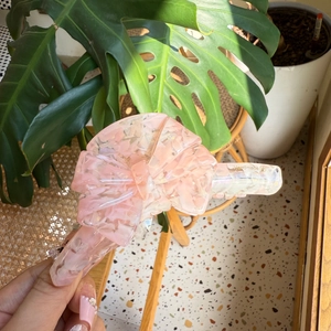 Detail view of pink acetate butterfly hair claw with handmade gold lettering