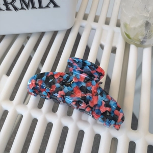 Large acetate hair claw clip with blue and pink abstract texture in a wavy shark design