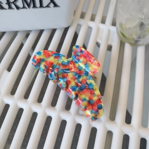 Close-up of a large acetate hair claw clip with a vibrant rainbow mosaic marble texture
