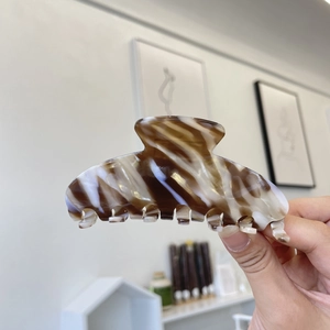 Detail showing marble textured acetate hair claw with coffee and ivory brown swirl patterns
