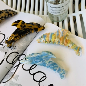 Détail de pinces à cheveux dauphin en acétate, motifs écaille, marbre bleu et macaron