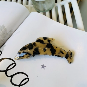 Détail d'une pince à cheveux dauphin avec motif écaille de tortue sur un magazine blanc