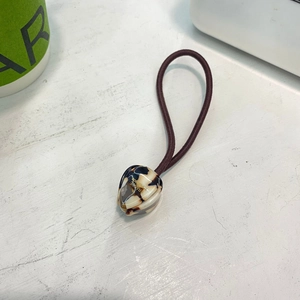 Élastique à cheveux marron avec perle écaille et texte France Handmade sur bureau blanc