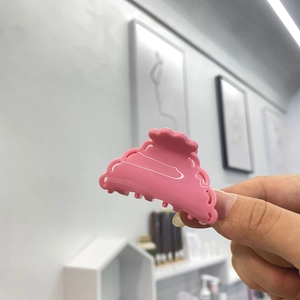 Pince à cheveux rose en acétate avec motif nuage évidé tenue pour démonstration