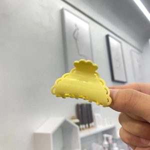 Détail macro d'une pince à cheveux jaune en acétate avec design ondulé creux et fini lisse