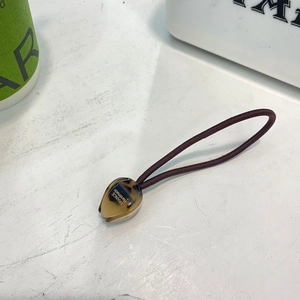 Détail d'un élastique marron avec perle en acrylique motif léopard et logo doré gravé