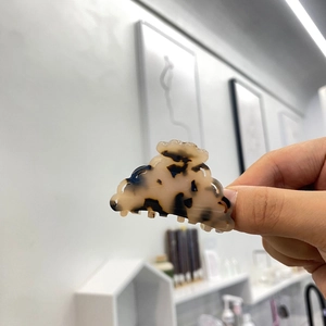 Vue détaillée d'une petite pince à cheveux écaille de tortue avec bords festonnés ambrés
