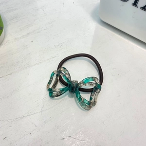 Elegant bow hair tie with marble texture resin pendant on a sleek black elastic band