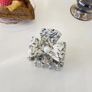 Detail of elegant acetate hair claw with marble pattern and white pearl center decor