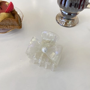 Detailed view of acetic acid hair claw with pearlescent bow and central pearl accent