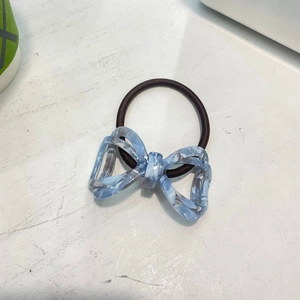 Detail of blue marble acetate bow on high-elasticity brown braided hair tie accessory
