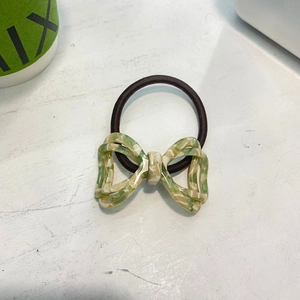 Detail of green and white marble patterned resin bow knot on a brown elastic hair tie