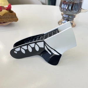 Elegant black and white acetate hair claw with cutout geometric patterns on a white table