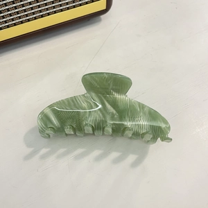 Close-up of green marble acetate hair claw clip with translucent mermaid finish detail