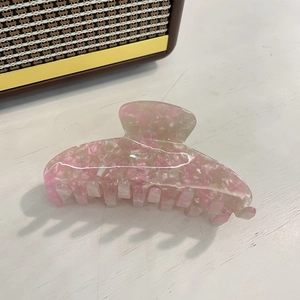 Detail of large acetate hair claw clip with pink and white marbled iridescent texture