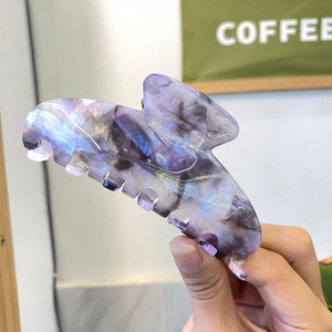 Detailed close-up of a large purple marble acetate shark hair claw clip with glitter finish