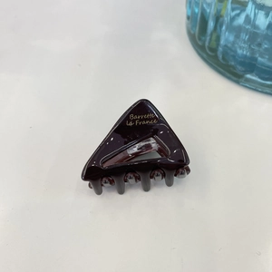 Vue détaillée de la pince à cheveux triangulaire marron foncé avec texte doré