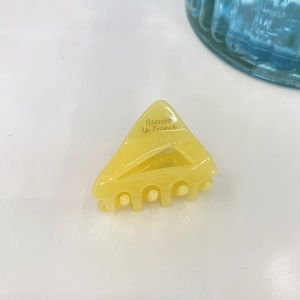 Détail de la pince à cheveux triangle jaune avec inscription Barrette La France