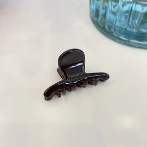 Detailed macro view of dark brown acetate hair claw clip with gold handmade lettering