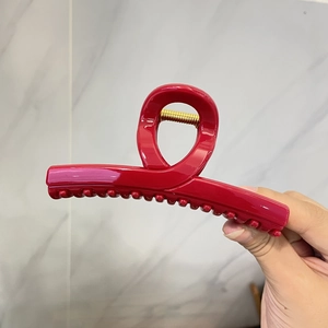 Détail d'une grande pince à cheveux élégante rouge avec ressort en métal doré