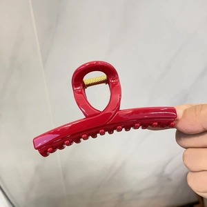 Détail d'une grande pince à cheveux rouge brillante avec un ressort en métal doré