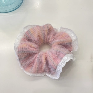 Dettaglio ravvicinato di elastico scrunchie in mohair rosa con bordo in pizzo bianco