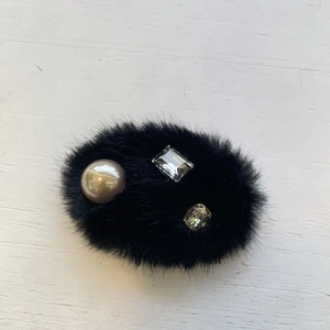 Détail d'une pince à cheveux noire en peluche avec perles et cristaux colorés
