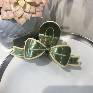 Vue détaillée d'une pince à cheveux nœud vert olive en acétate avec des bords crème