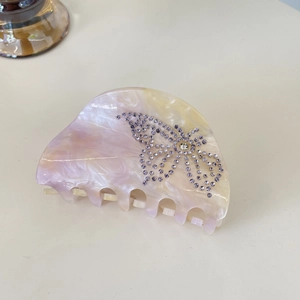 Detailed macro view of acetate butterfly hair claw with marble texture and purple rhinestones