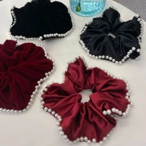 Close-up of pearl-edged scrunchies in velvet and satin fabrics with detailed stitching