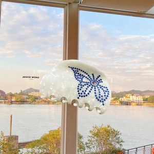 Detailed macro view of pearl white hair claw clip with blue rhinestone butterfly design
