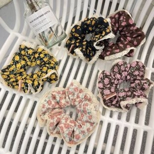 Floral scrunchies with white lace embroidery in five assorted colors on a chair