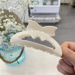 Elegant cream bow hair claw clip made of acrylic with a hollow butterfly design