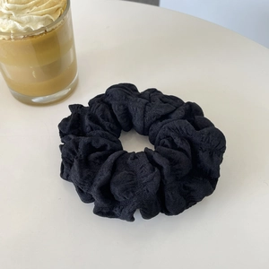 Elegant black puff scrunchie with bubble texture on a clean white table setting