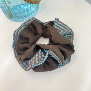 Detailed view of brown and blue silk-like scrunchie with retro wave patterns