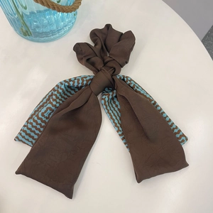 Close-up of brown wavy print scrunchie with long ribbons on white surface