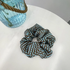 Detail view of large scrunchie with blue and brown zigzag wavy pattern on white table